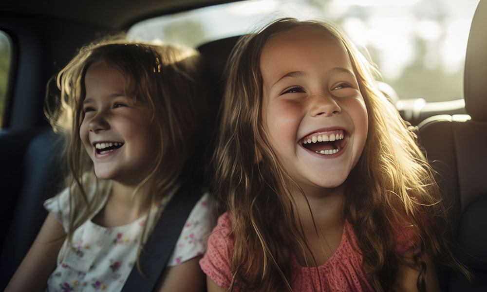 Dos niñas sonriendo mientras viajan en un coche