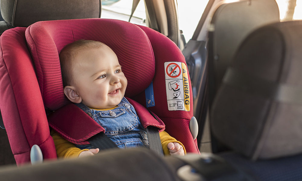 Bebe sonriendo mientras se encuentra en silla de auto