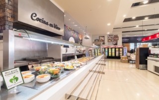 Cocina en vivo detrás de barra autoservicio llena de ensaladas listas para coger y comer