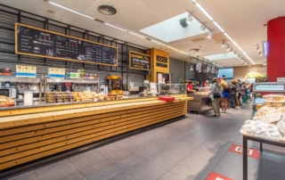 Barra de Self Service donde se observa productos de bollería, zona recién hecho y clientes al fondo