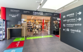 Acceso a tienda junto a cartelería que indica aseos, restaurante y self service