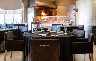 Mesa para cuatro personas para almorzar en el restaurante Abades Mérida, al final se observa llamas de barbacoa