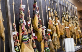Varios jamones ibéricos pata negra colgados en el área de servicio Abades Mérida listos para comprar y llevar