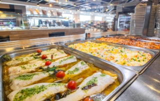 Bandeja de comida donde se aprecia pescado, arroz, macarrones y carne