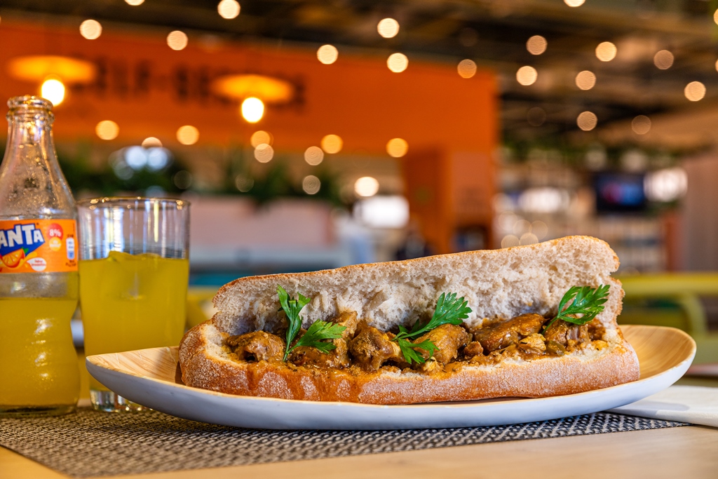 Bocadillo de carne en salsa en pan de chapata junto a refresco fanta de naranja