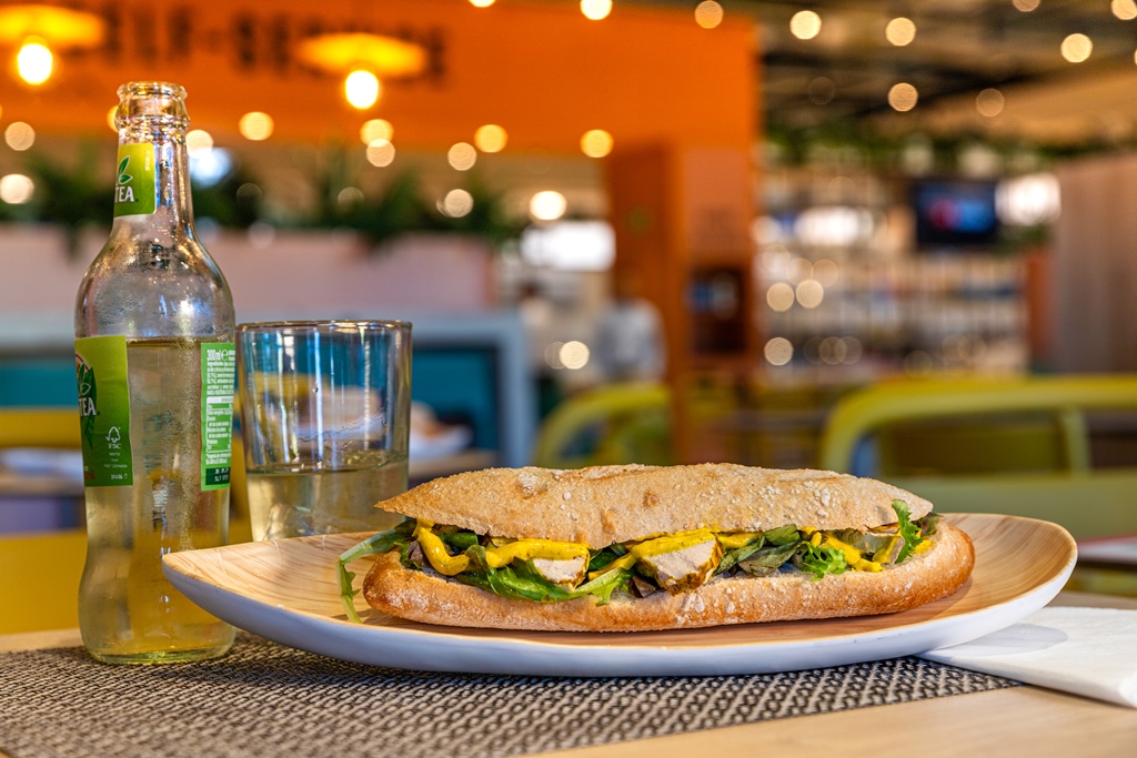 Bocadillo de pechuga de pollo al curry junto a refresco de té al limón